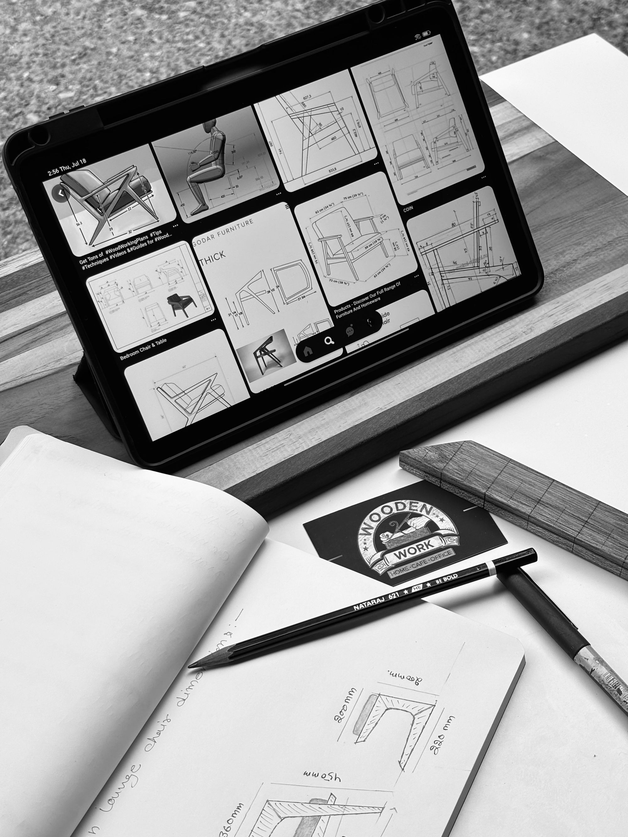 Tablet mit Möbelentwürfen neben einem Notizbuch mit bemaßten Stuhlskizzen