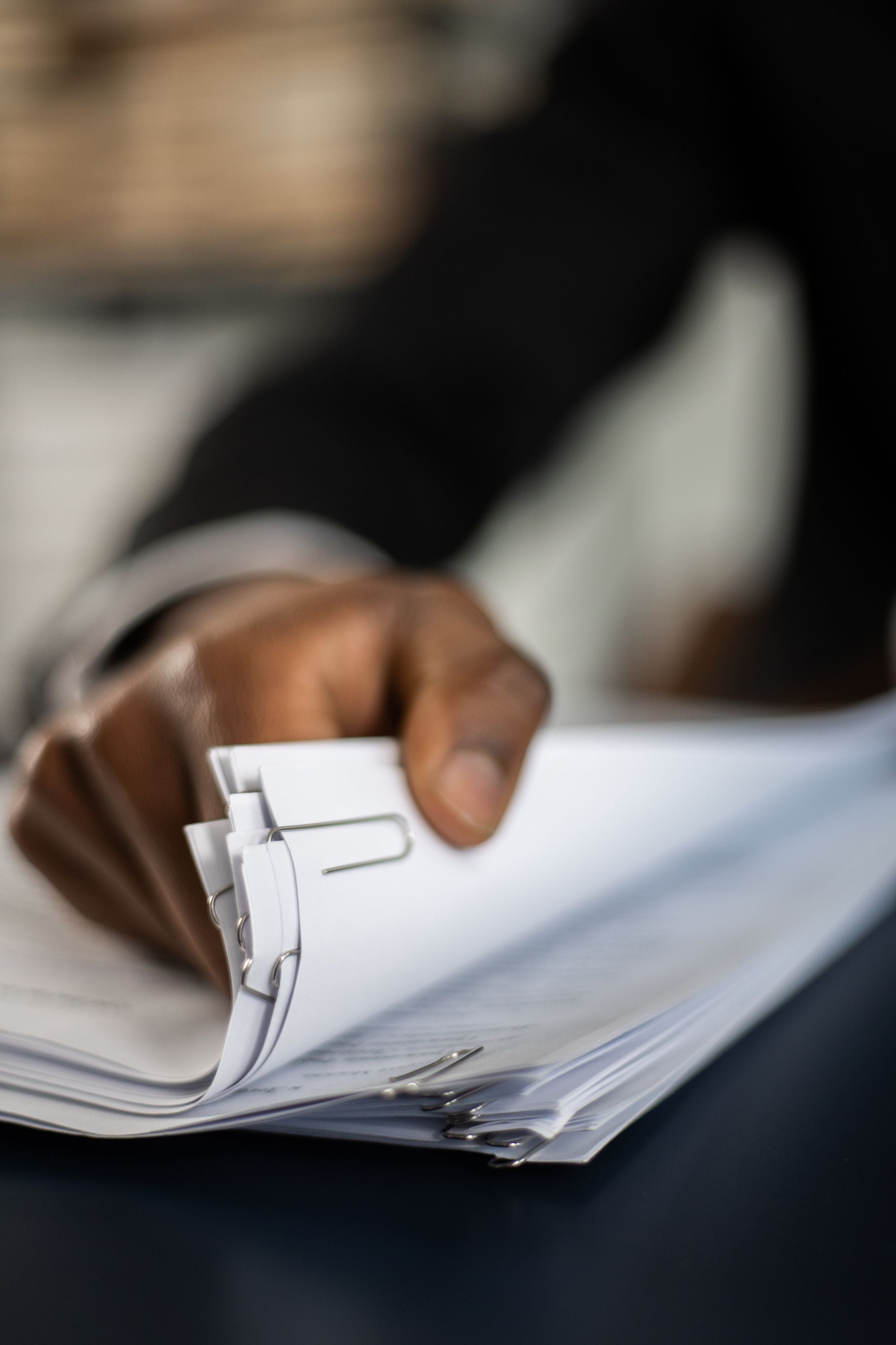 Hand an einem Stapel weißer Papierunterlagen mit Klammern